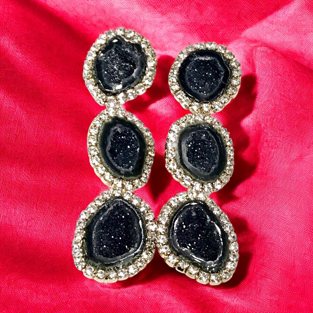Black stone earrings on a pink red background