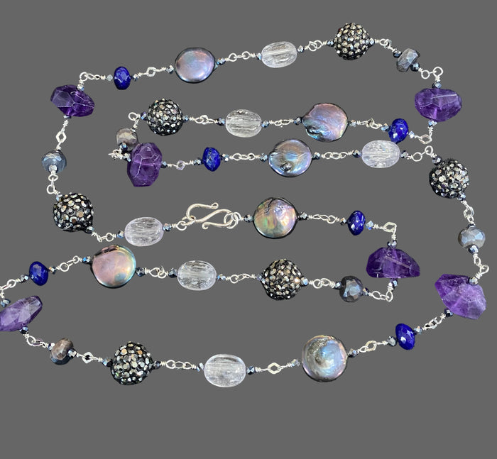 Long wire wrapped necklace with blue purple gemstones and sterling silver on a grey background