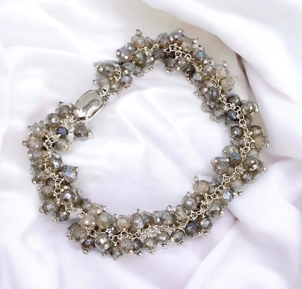  Mystic labradorite wire wrapped bracelet lying on white draped fabric