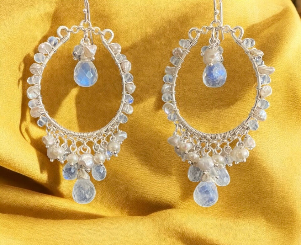 Silver hoop earrings with gemstones on a yellow fabric background