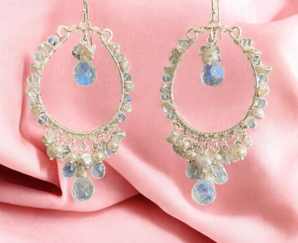 Pair of hoop earrings with gemstones on a pink fabric background