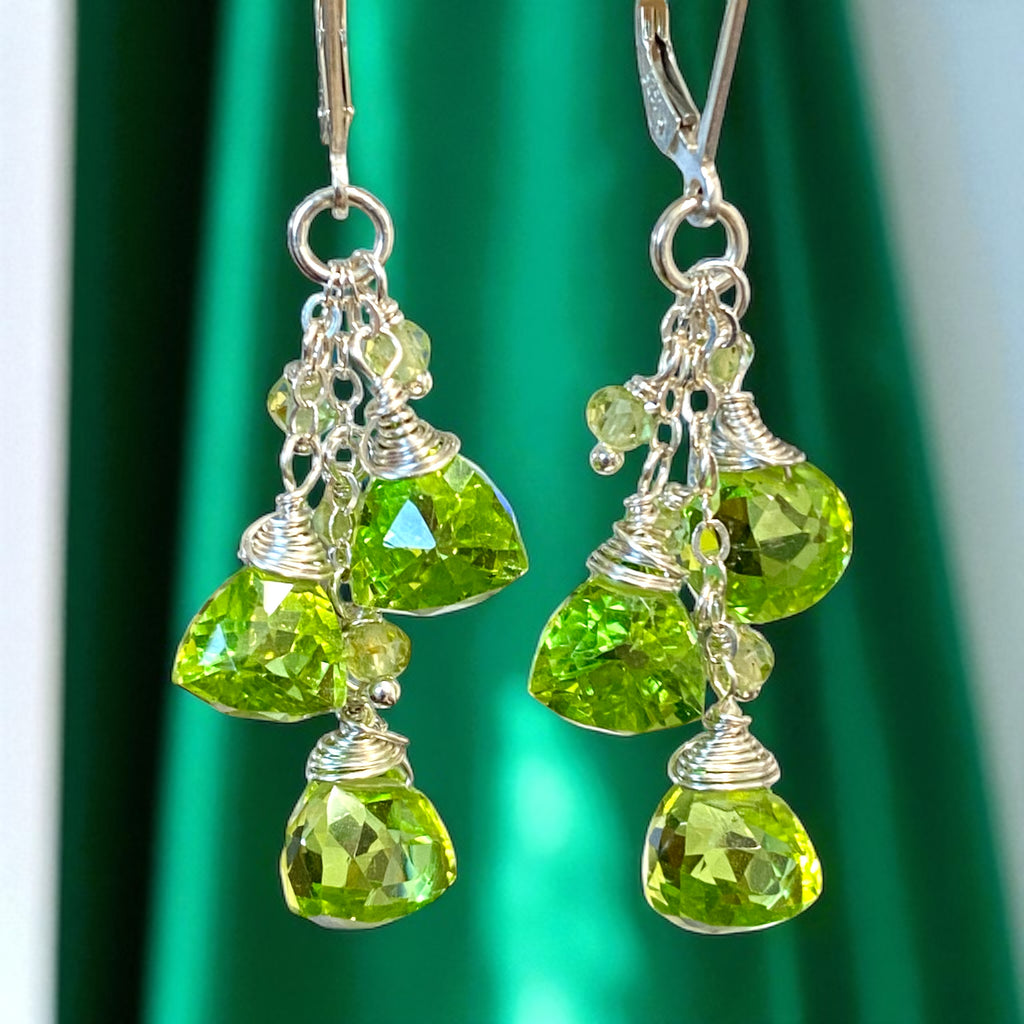 Green gemstone earrings with silver hooks on a green background