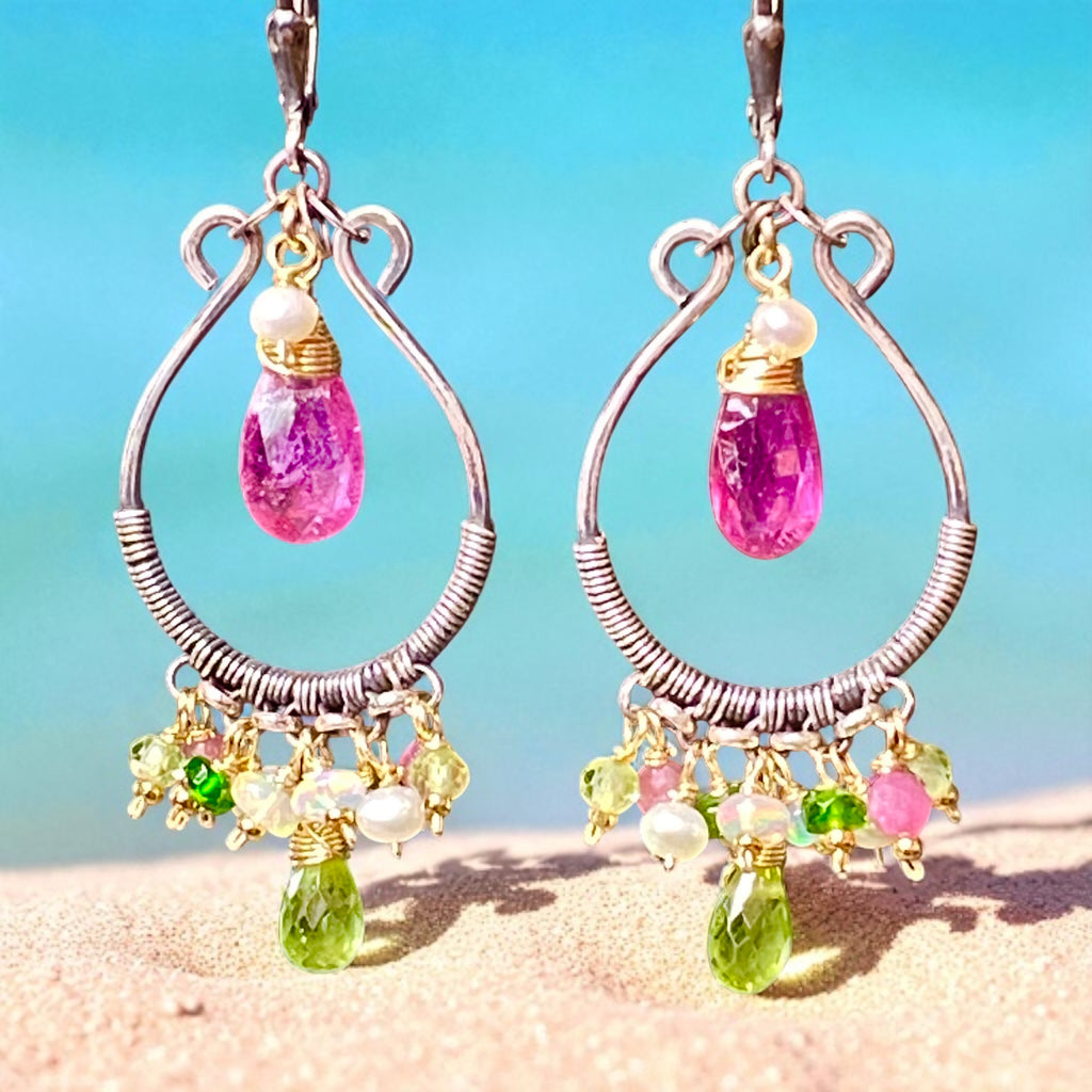 Pair of earrings with colorful gemstones on a beach background