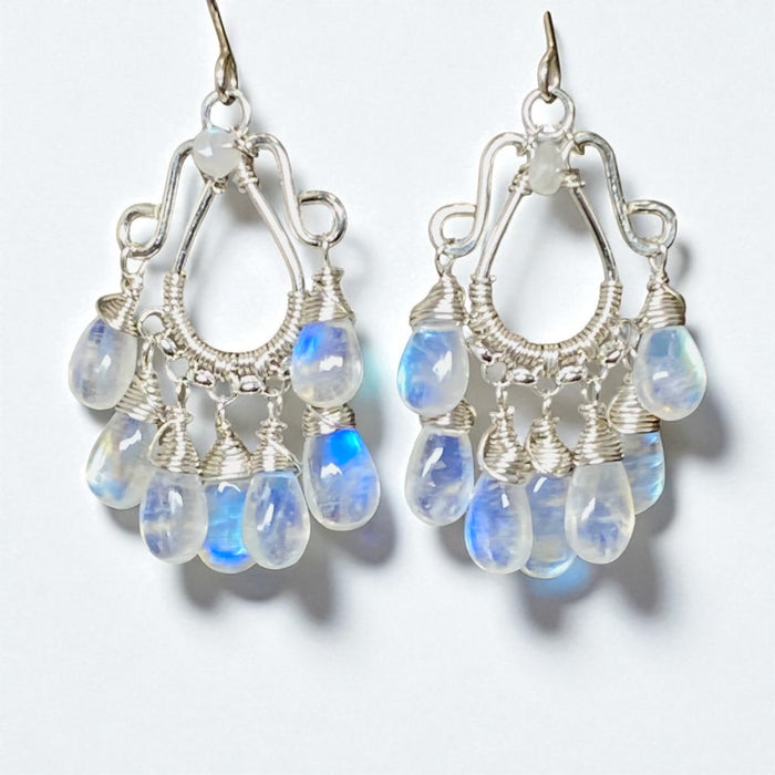 Silver earrings with teardrop-shaped blue gemstones on a white background
