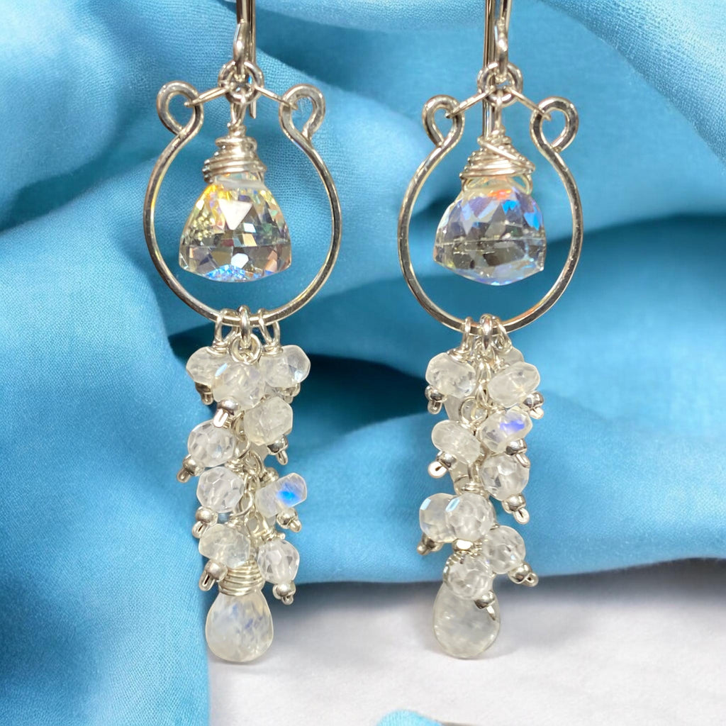 Pair of sterling silver chandelier tassel earrings with white gemstones on a blue fabric background