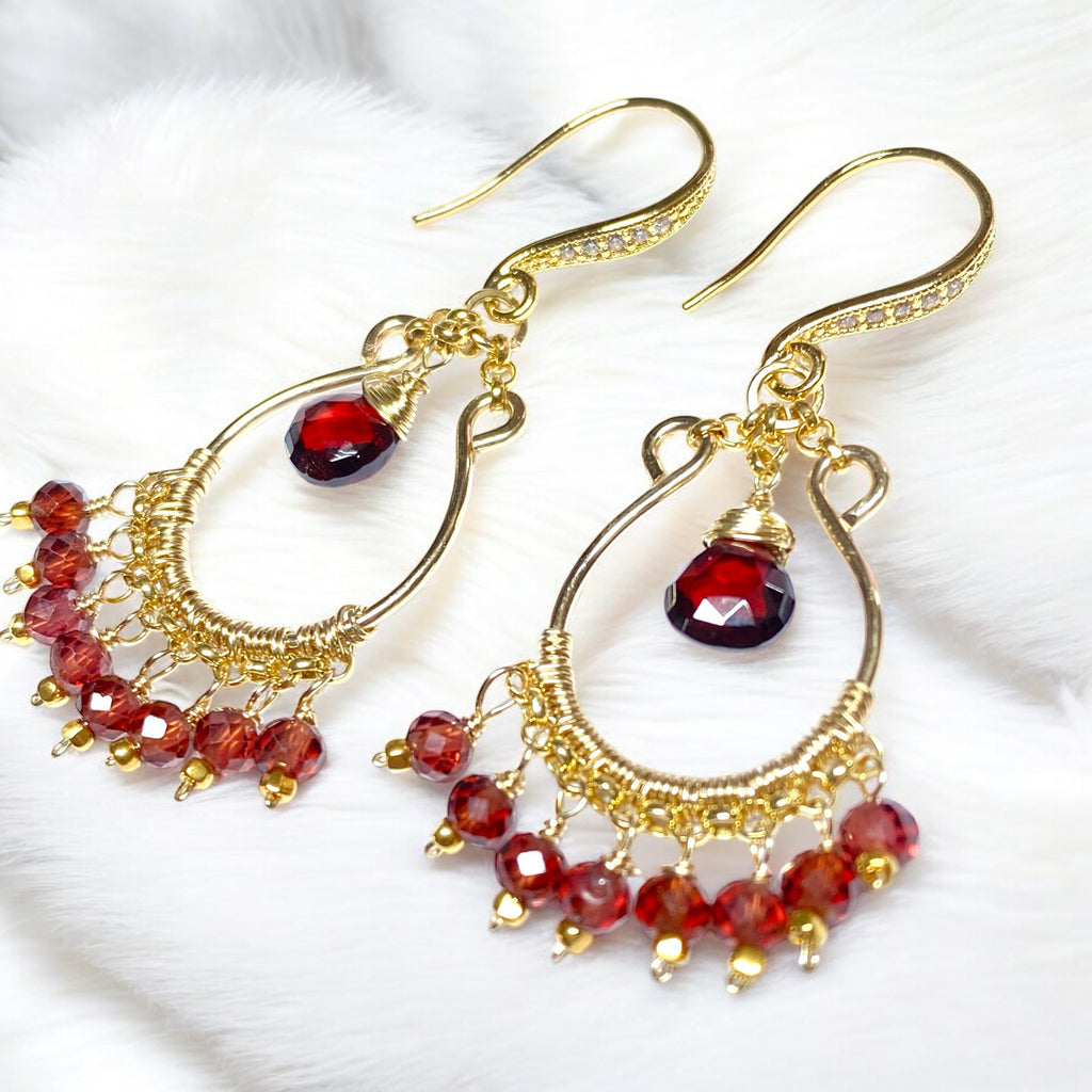 Red garnet chandelier hoop earrings 14kt gold fill lying on white fabric