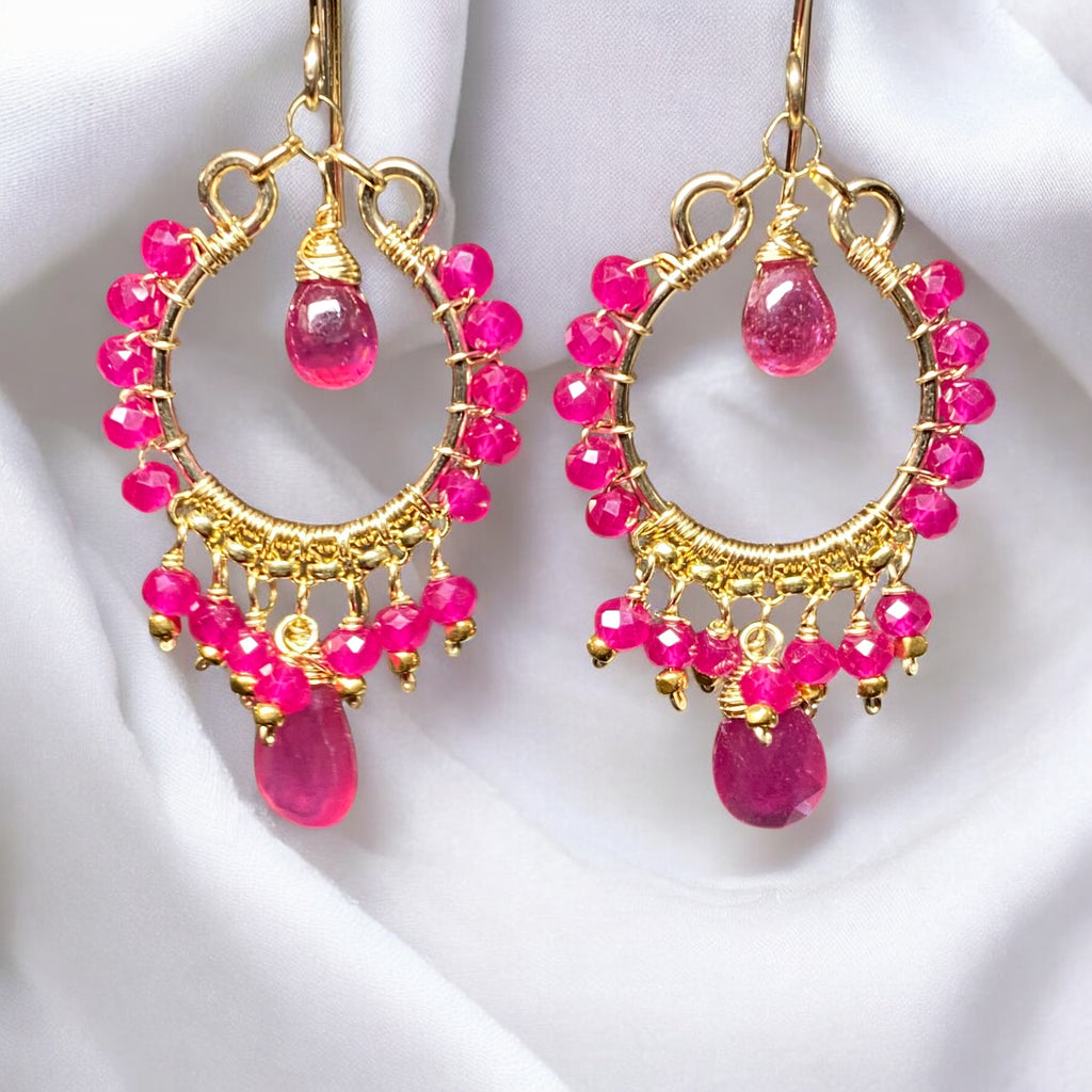 Red ruby pink sapphire gold chandelier hoop earrings dangling in front of draped white fabric