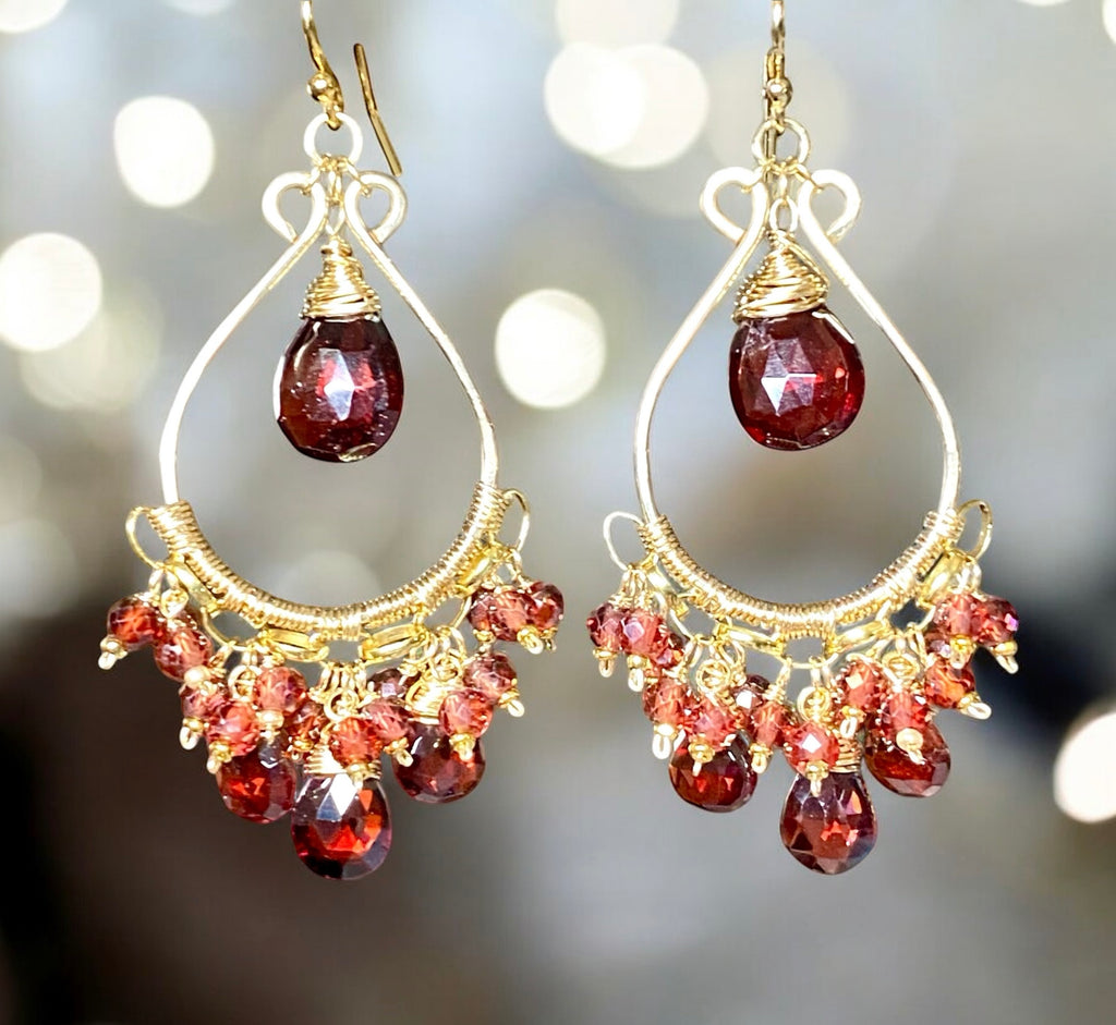 Red garnet chandelier earrings 14kt gold fill on blurred bokeh lights background