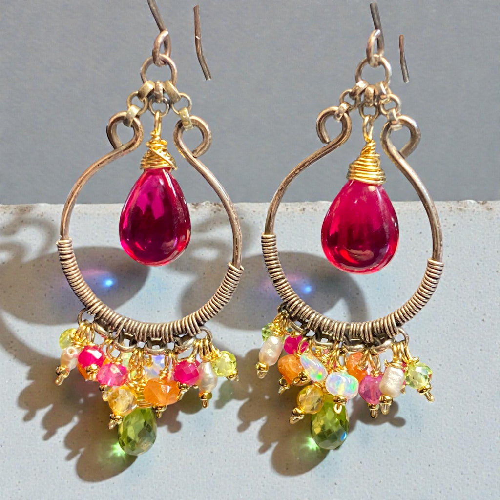 Handmade mixed metal hoop earrings with pink rubellite and peridot on grey surface