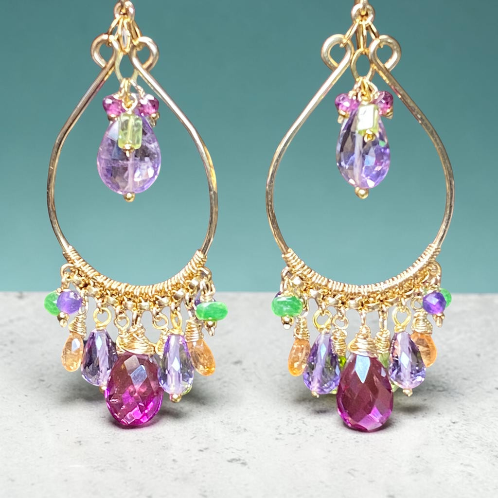  Colorful gemstone chandelier hoop earrings in violet, green and pink against aqua wall and mottled grey marble base — handmade gold fill
