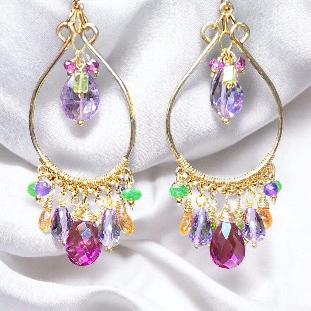  Multi gemstone gold fill hoop earrings dangling against artfully draped white fabric — peridot, amethyst, violet quartz, mandarin garnet