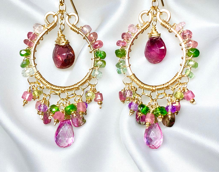 Colorful earrings with gemstones on a white fabric background

Details