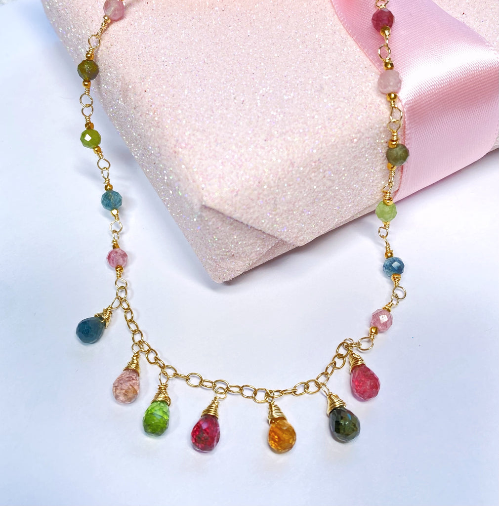 Necklace with multicolored gemstones on a light pink fabric background