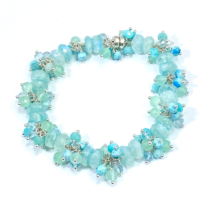 A wire wrapped cluster bracelet with turquoise and aqua moonstone beadsl, shown in sterling silver on white background.